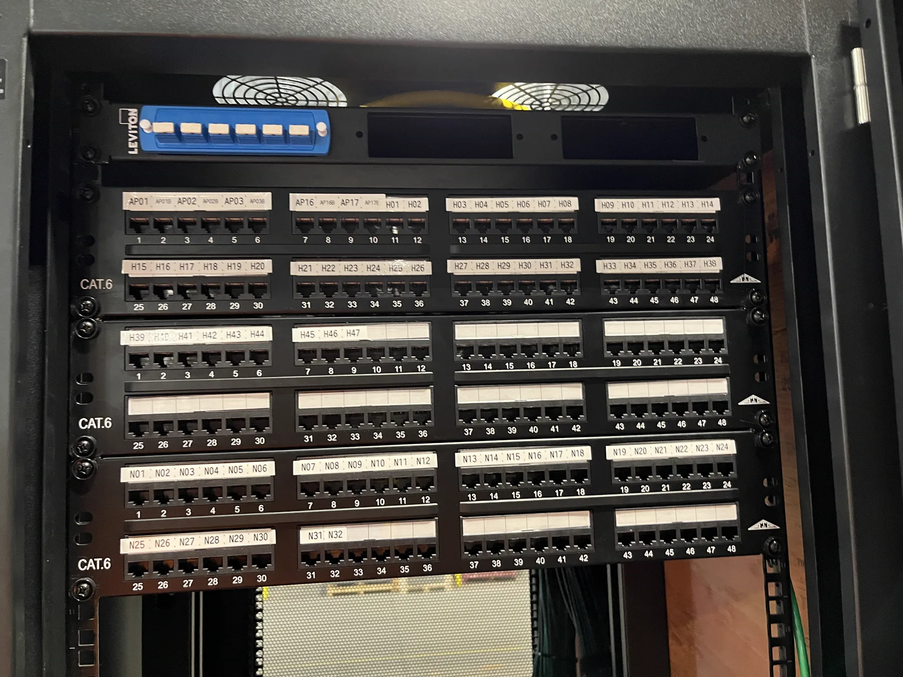 Completed warehouse communications rack with labeled copper patch panels